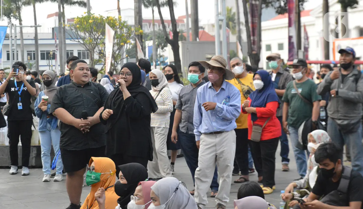 Dua orang penerjemah bahasa isyarat yang sedang memegang mic dan berpakaian serba hitam pada Sesi NGOBAR TULI (Ngobrolbareng Tuli) di Festival #IniJakarta2022, Kota Tua, Jakarta, Minggu (18/9/2022). Seorang penerjemah bahasa isyarat harus mengenakanpakaianberwarna hitam polos atau biru gelap saat bertugas dan tidak memakai perhiasan atau aksesori yang dapat mengalihkan perhatian teman tuli saat menerjemahkan bahasa isyarat.(Liputan6.com/Magang/Aida Nuralifa)