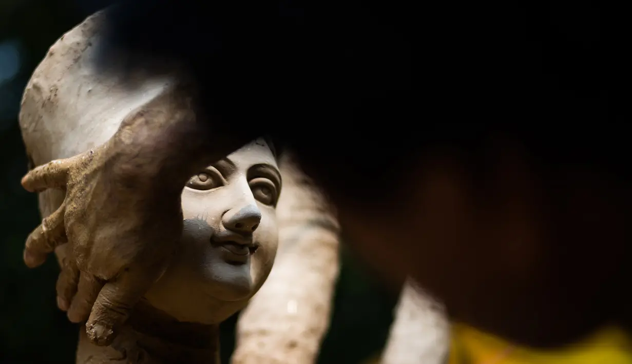 Seorang perajin membuat patung dewi Durga menjelang festival 'Durga Puja' di sebuah workshop di New Delhi, India, Rabu (14/10/2020). Durga Puja merupakan festival tahunan di Asia Selatan untuk memuja dewi Durga dari agama Hindu. (Photo by Jewel SAMAD / AFP)