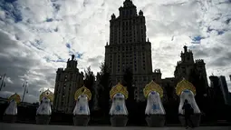 Seorang pria mengambil gambar "benda seni Matryoshki", tujuh boneka bersarang tradisional Rusia "matryoshka" dengan hiasan kepala "kokoshnik", di depan hotel pencakar langit era Soviet "Ukraina" di pusat kota Moskow (9/9/2021).  (AFP/Kirill Kudryavtsev)