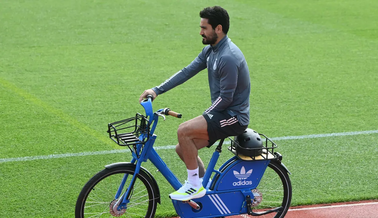 Gelandang Jerman, Ilkay Gundogan tiba dengan sepeda sebelum sesi latihan menjelang UEFA EURO 2020 di World of Sports Campus di Herzogenaurac (11/6/2021). Pada pertemuan pertama, Jerman akan bertemu Prancis pada grup F di Allianz Arena, Rabu (16/6). (AFP/Christof Stache)