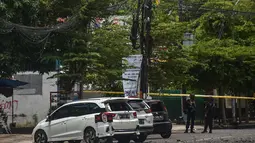 Polisi berjaga di samping kendaraan yang rusak setelah ledakan di luar sebuah gereja di Makassar (28/3/2021). Sebuah benda diduga bom meledak di Gereja Katedral Makassar pada Minggu (28/3/2021) pagi. (AFP/Indra Abriyanto)