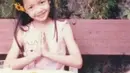 Pertama adalah foto masa kecil Lisa, dengan bunga berwarna kuning yang diselipkan ke telinga, Lisa kecil tersenyum manis ke kamera sembari menangkupkan tangannya di depan dada. (Foto: Instagram/ roses_are_rosie)