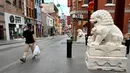 Seorang pria membawa belanjaannya di jalan sepi di Chinatown Melbourne, Australia, Selasa (19/10/2021). Melbourne bersiap mencabut aturan penguncian pekan ini setelah kota tersebut berada dalam enam pekan lockdown selama 262 hari atau hampir sembilan bulan sejak Maret 2020. (William WEST/AFP)