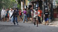 Massa melempar batu ke arah aparat keamanan saat terjadi bentrok di kawasan Slipi, Jakarta Barat, Rabu (22/5/2019). Massa yang terlibat kerusuhan tarpantau sebagian besar masih berusia remaja. (Liputan6.com/Gempur Muhammad Surya)
