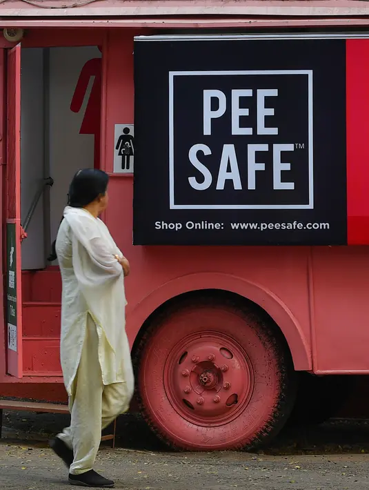 Foto pada 9 Februari 2020 menunjukkan seorang perempuan  berjalan melewati toilet keliling di sebuah bus di taman umum di Pune, India. Proyek Ti Toilet, sebuah bus yang diubah menjadi toilet dan diluncurkan pada tahun 2016, adalah gagasan Ulka Sadalkar dan Rajeev Kheer. (Indranil MUKHERJEE/AFP)