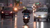 Seorang pengendara sepeda motor berkendara di sepanjang jalan di bawah hujan lebat di Chennai ketika topan Nivar mendekati pantai tenggara negara itu, (25/11/2020). (AFP/Arun Sankar)