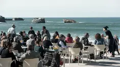 Warga dan turis menikmati minuman di sebuah kafe selama cuaca musim dingin yang hangat di sepanjang garis pantai kota Biarritz di Perancis barat (17/2). Kota ini terletak di region Aquitane, Departemen Pyrénées-Atlantiques. (AFP Photo/Iroz Gaizka)