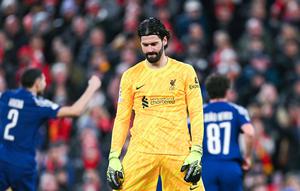 Kiper Liverpool, Alisson Becker, tampak kecewa setelah ditaklukkan PSG lewat adu penalti 0-1 (1-4) dalam laga leg kedua 16 besar Liga Champions 2024/2025 yang digelar di Anfield, Rabu (12/3/2025) dini hari WIB. (AFP/Oli Scarff)