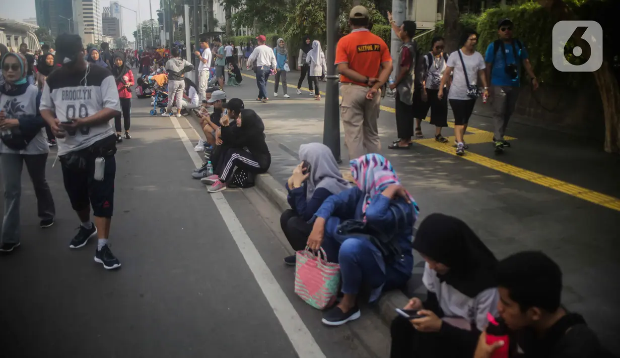 Petugas Satpol PP berjaga saat warga berolahraga pada car free day (CFD) di kawasan Bundaran HI, Jakarta, Minggu (17/11/2019). Tidak adanya PKL membuat kawasan Bundaran HI tampak bersih dan rapi. (Liputan6.com/Faizal Fanani)