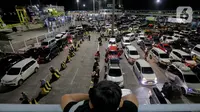 Seorang anak memperhatikan antrean mobil yang akan masuk ke dalam kapal penyeberangan di Pelabuhan Merak, Kota Cilegon, Banten, Jumat (28/3/2025) dini hari. (Liputan6.com/Herman Zakharia)