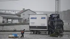 Seorang pria berjalan di sepanjang Fiskhamnen (pelabuhan nelayan) yang banjir setelah sungai Gota Alv meluap akibat hujan deras di Gothenburg, Swedia, Selasa, 8 Agustus 2023.  (Björn Larsson Rosvall/TT News Agency via AP)