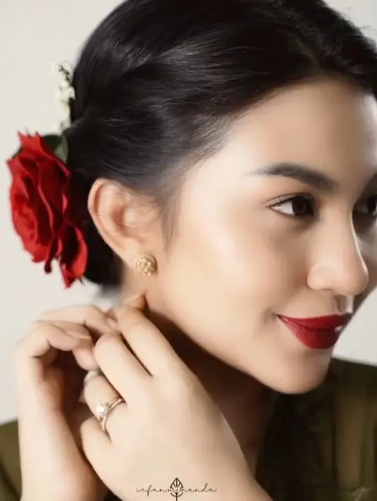 Kecantikannya makin paripurna dengan pernak-pernik simpel tapi memikat. Rona merah terpancar dari bibir dan sanggul mawar di rambutnya. [Instagram/arieltatum]