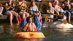 Catherine Smith, dari Florida, merayakan setelah memenangkan perlombaan dalam event West Coast Giant Pumpkin Regatta di Tualatin, Oregon, Amerika Serikat pada 16 Oktober 2022. Para peserta juga menggunakan macam - macam kostum unik saat balapan berlangsung. (Photo by Wesley Lapointe / AFP)