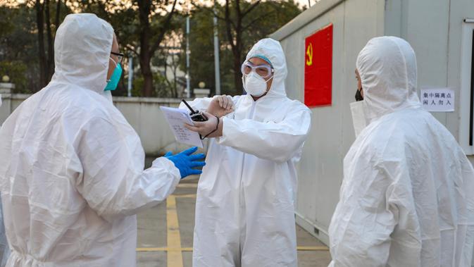 Para pekerja berpakaian pelindung berbincang di luar hotel yang digunakan dalam isolasi medis virus corona di Wuhan, Provinsi Hubei, China, Senin (3/2/2020). (Chinatopix via AP)