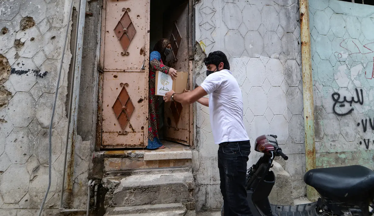 Warga menerima jatah makanan dari Relawan Irak di asosiasi lokal selama bulan Muslim Ramadhan di kota Mosul utara (7/5/2021). (AFP Photo/Zaid AL-Obeidi)