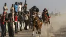 Warga menyaksikan para joki memacu kudanya saat bersaing dalam balap kuda di Rafah, Jalur Gaza, Palestina, Selasa (10/9/2019). Balapan kuda tradisional Palestina tersebut digelar di bekas lokasi bandara Jalur Gaza yang telah hancur. (AFP Photo/Said Khatib)