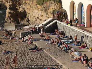 Orang-orang berjemur di pantai Biarritz, barat daya Prancis, Rabu (27/10/2021). Suhu di Prancis barat daya mencapai 20 derajat Celcius (68 Fahrenheit). (AP Photo/Bob Edme)