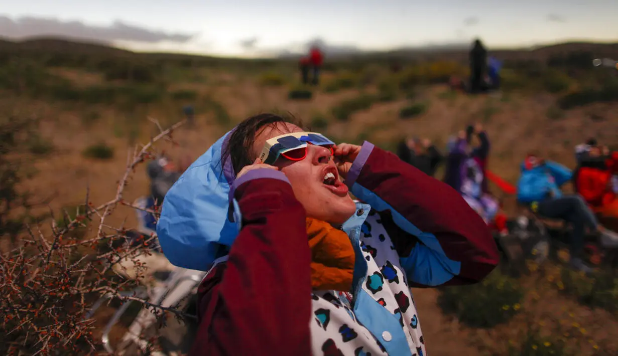 Seorang pemuda memakai kacamata pelindung untuk menyaksikan efek "cincin berlian" saat terjadi gerhana matahari total di Piedra del Aguila, Argentina, Senin (14/12/2020). Gerhana matahari total terlihat dari wilayah Patagonia utara Argentina dan dari Araucania di Chili. (AP Photo/Natacha Pisarenko)