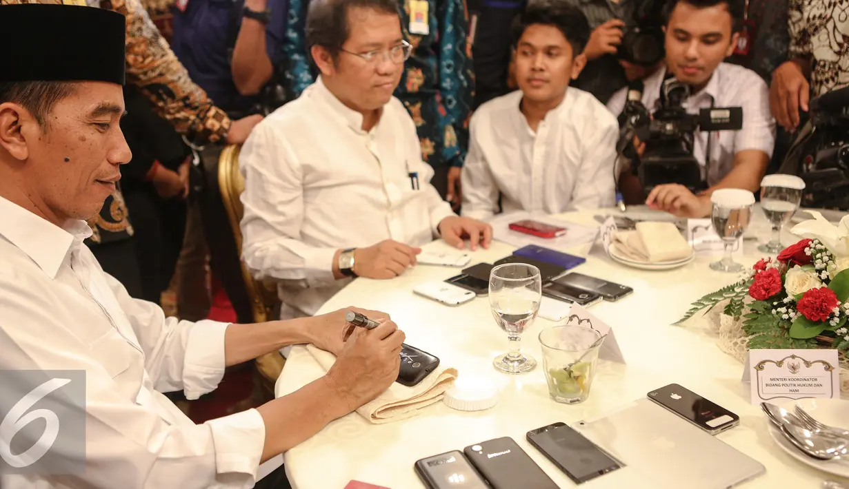 Presiden Joko Widodo menandatangani sejumlah telepon seluler milik wartawan usai berbuka puasa di Istana Negara, Jakarta, Senin (6/7/2015). Sekitar 300 wartawan menghadiri acara buka puasa bersama Jokowi tersebut. (Liputan6.com/Faizal Fanani)