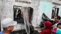 Warga menyaksikan tim penyelidik bekerja di lokasi kebakaran pabrik korek gas di Binjai, Langkat, Sumatera Utara, (21/6/2019). Pihak kepolisian masih melakukan penelusuran, terutama jenazah korban. (Ivan Damanik/AFP)