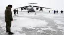 Seorang perwira Rusia berdiri dekat pesawat kargo militer Il-76 yang mendarat di Pulau Alexandra Land dekat Nagurskoye, Rusia, Senin (17/5/2021). Pangkalan militer ini dipenuhi rudal, radar serta landasan pacu yang dapat menangani semua jenis pesawat. (AP Photo/Alexander Zemlianichenko)