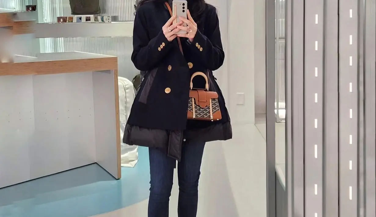 Manisnya gaya Dian Sastro dengan coat hitam dengan kancing emas, dipadunya mengenakan celana jeans. [Foto: Instagram/therealdisastr]