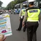 Petugas Dinas Perhubungan menunjukkan selebaran sosialisasi pemberlakuan sistem ganjil genap di pintu masuk Gardu Tol Cibubur 2, Jakarta, Senin (16/4). Aturan ini berlaku untuk kendaraan pribadi atau golongan I dan II. (Liputan6.com/Faizal Fanani)