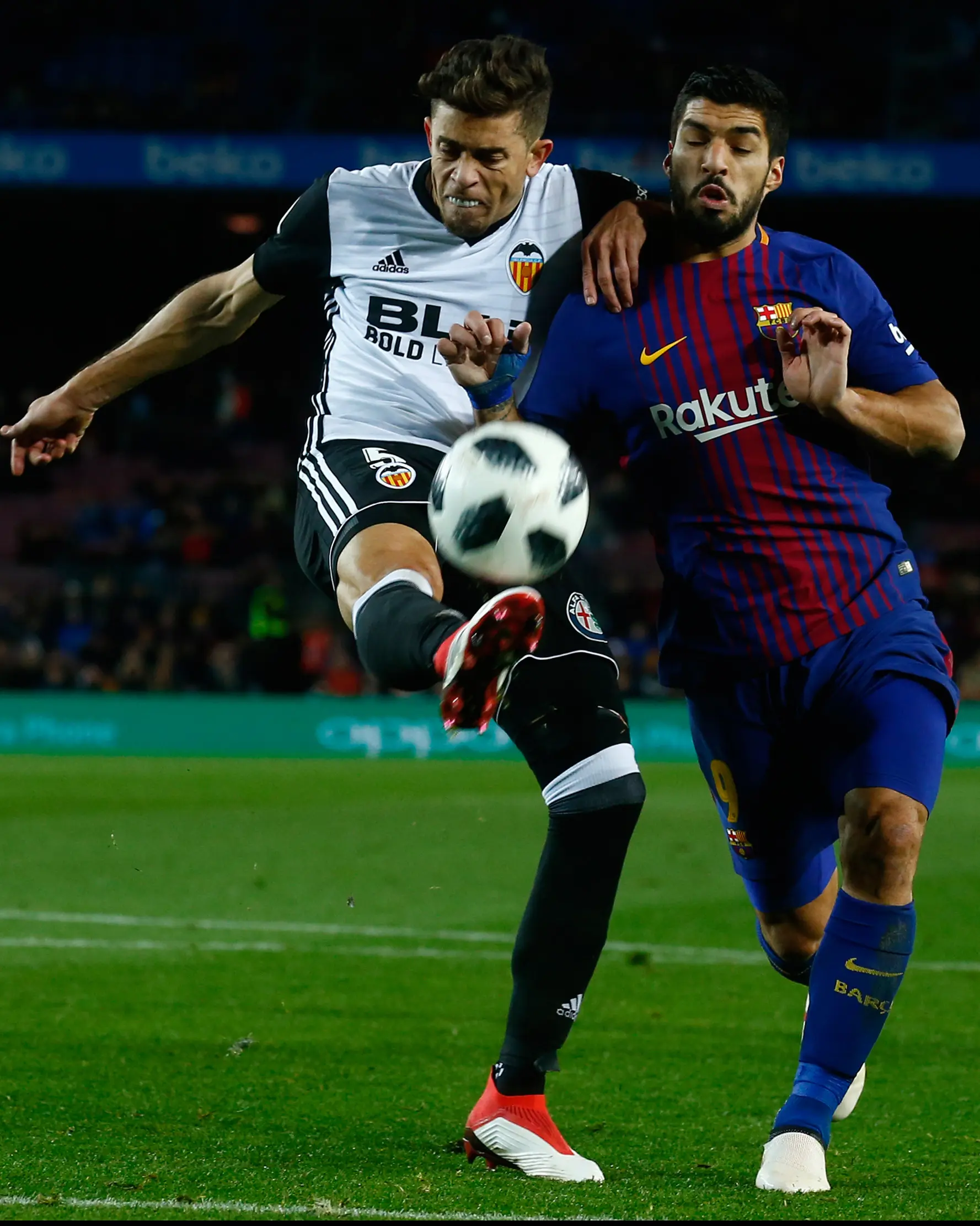 Pemain Barcelona, Luis Suarez berebut bola dengan pemain Valencia, Gabriel Paulista pada semifinal pertama Copa del Rey di Stadion Camp Nou, Jumat (2/2). Menang 1-0, peluang Barcelona untuk melaju ke partai final terbuka lebar. (AP/Manu Fernandez)