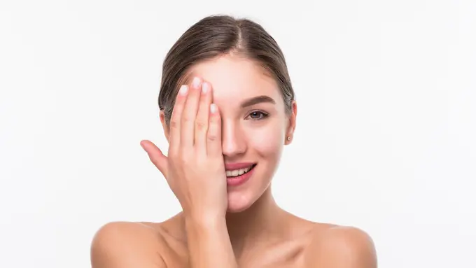 Seorang perempuan dengan rambut digulung tersenyum sambil menutup sebagian wajahnya dengan tangan (Foto Dok: Freepik/diana.grytsku)