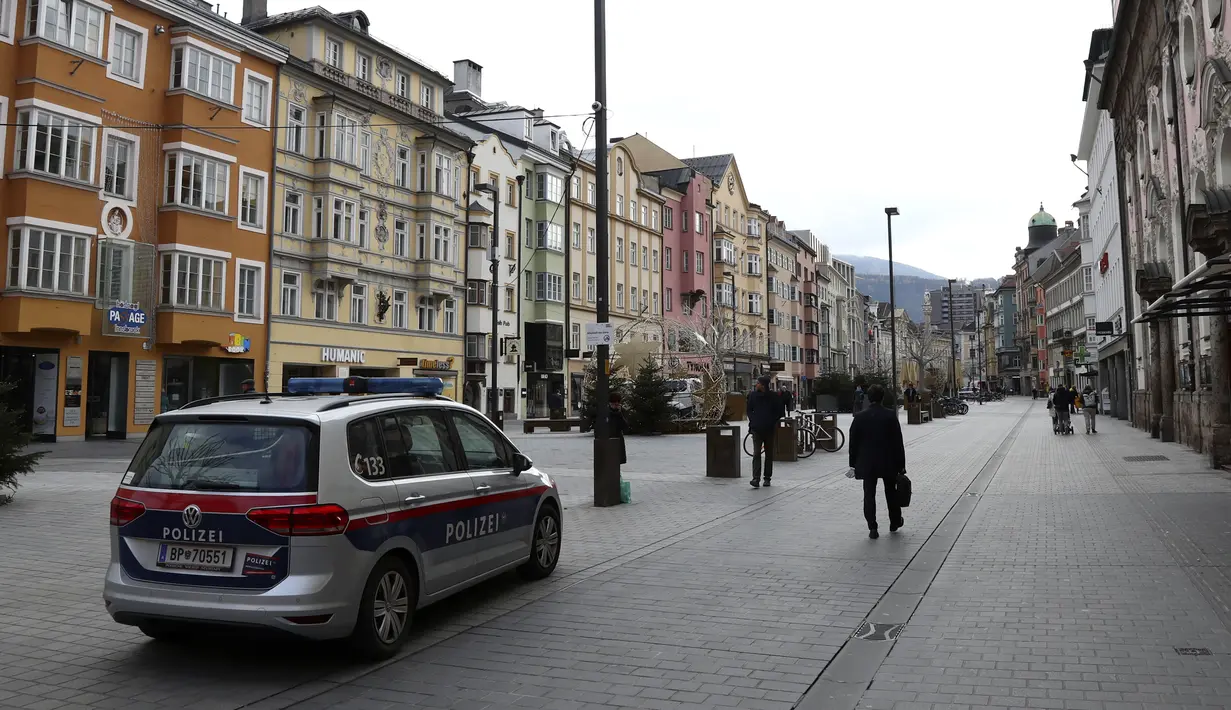 Mobil polisi diparkir di alun-alun yang sepi di Innsbruck, Austria, Selasa (17/11/2020). Pemerintah Austria telah memberlakukan pengetatan aturan covid-19 yang mencakup penutupan sekolah dan toko-toko nonesensial hingga 6 Desember 2020, seiring gelombang kedua virus corona. (AP/Matthias Schrader)