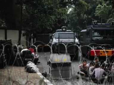 Petugas berjaga dibalik kawat berduri yang dipasang didepan Kedutaan Besar Myanmar, Jakarta, Rabu (6/9).  Jelang aksi yang rencananya akan dihadiri puluhan ribu orang, pihak kepolisian berjaga di sekitar Kedubes Myanmar. (Liputan6.com/Faizal Fanani)