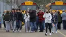 Orang tua berjalan pergi dengan anak-anak mereka dari tempat parkir Meijer, di mana banyak siswa berkumpul menyusul situasi penembak aktif di Oxford High School di Oxford, Michigan (30/11/2021). Polisi telah menahan seorang tersangka penembak. (Eric Seals/Detroit Free Press via AP)