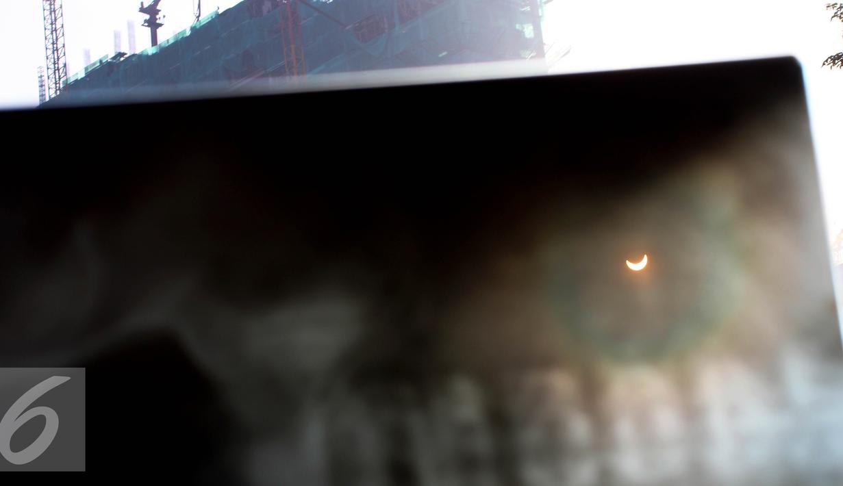 Warga mengunakan film bekas ronsen melihat proses Gerhana Matahari Total (GMT) 2016 di halaman Taman Ismail Marzuki (TIM), Jakarta, Rabu (9/3). Fenomena alam ini terjadi setiap 350 tahun. (Liputan6.com/Fery Pradolo)