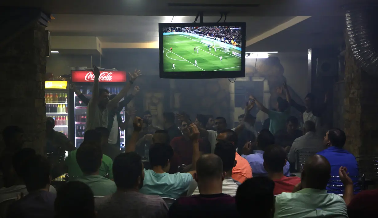 Warga Palestina menyaksikan pertandingan sepak bola El Clasico antara Real Madrid dan Barcelona FC di sebuah kafe di kota Ramallah, Tepi Barat (6/5). Real Madrid dan Barcelona meraih hasil imbang 2-2 di pertandingan tersebut. (AFP Photo/Abbas Momani)