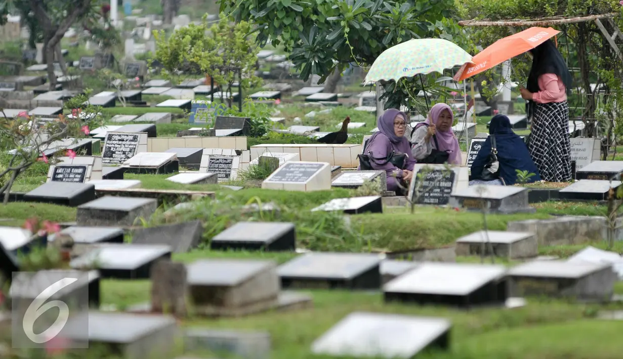 Warga tengah berziarah di makam kerabatnya di TPU Karet Bivak, Jakarta, Rabu (13/7). Sudin Pertamanan dan Pemakaman Jakarta Pusat akan buat ratusan lubang biopori di TPU Karet Bivak agar makam tidak tergenang saat hujan. (Liputan6.com/Yoppy Renato)