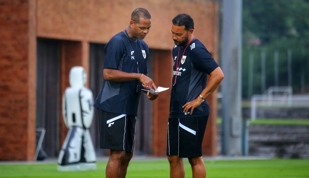 Pelatih kepala Timnas Indonesia, Patrick Kluivert (kiri) berdiskusi dengan asisten pelatih Denny Landzaat saat melakukan latihan persiapan menjelang laga Ronde 3 Kualifikasi Piala Dunia 2026 melawan China di Bali United Training Center, Bali, pada Selasa sore (23/05/2025). (Bola.com/Alit Binawan)