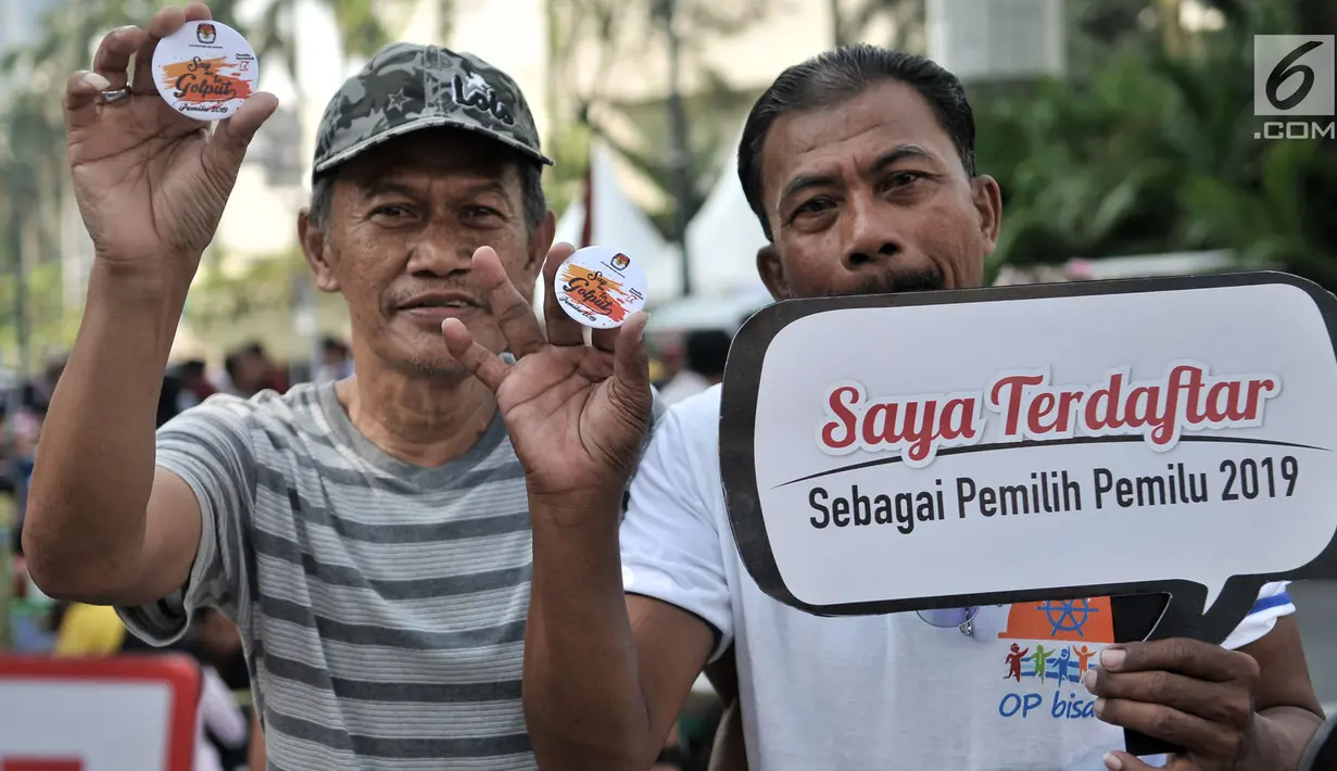 Warga menunjukan pin anti golput usai melakukan pendaftaran daftar pemilih tetap (DPT) di kawasan Car Free Day, Jakarta, Minggu (21/10). Pos pendaftaran ini bertujuan mendata warga yang belum terdaftar dalam DPT Pemilu 2019. (Merdeka.com/Iqbal S. Nugroho)