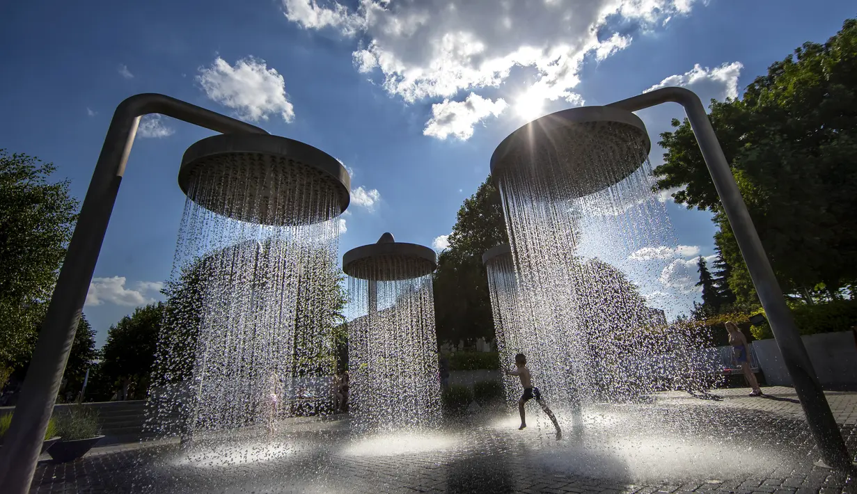 Seorang anak mendinginkan diri di air mancur umum di Vilnius, Lithuania, 26 Juni 2022. Gelombang panas berlanjut di Lithuania saat suhu naik hingga 32 derajat Celcius (89,6 derajat Fahrenheit). (AP Photo/Mindaugas Kulbis)