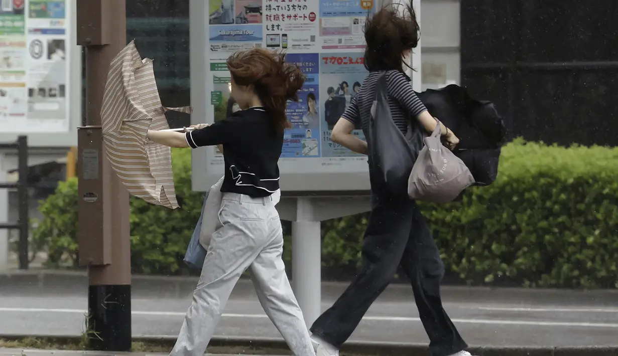 Orang-orang berjalan di tengah hujan badai yang dibawa oleh Badai Tropis Khanun di Kagoshima, Jepang selatan Rabu, 9 Agustus 2023. (Kyodo News via AP)