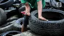 Pekerja memotong ban mobil bekas di kawasan Petamburan, Jakarta, Minggu (12/12/2021). Ban bekas ini nantinya akan dilebur untuk dijadikan minyak serta bahan baku pembuatan aspal. (Liputan6.com/Faizal Fanani)