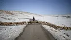 Seorang gembala menyeberang jalan dengan domba-dombanya di antara salju di desa Amazigh Timahdite di Atlas Tengah, dekat Azrou, Maroko (4/12/2021). Desa Timahdite Maroko yang terpencil, terletak di gunung tertinggi di Afrika Utara. (AP Photo/Mosa'ab Elshamy)