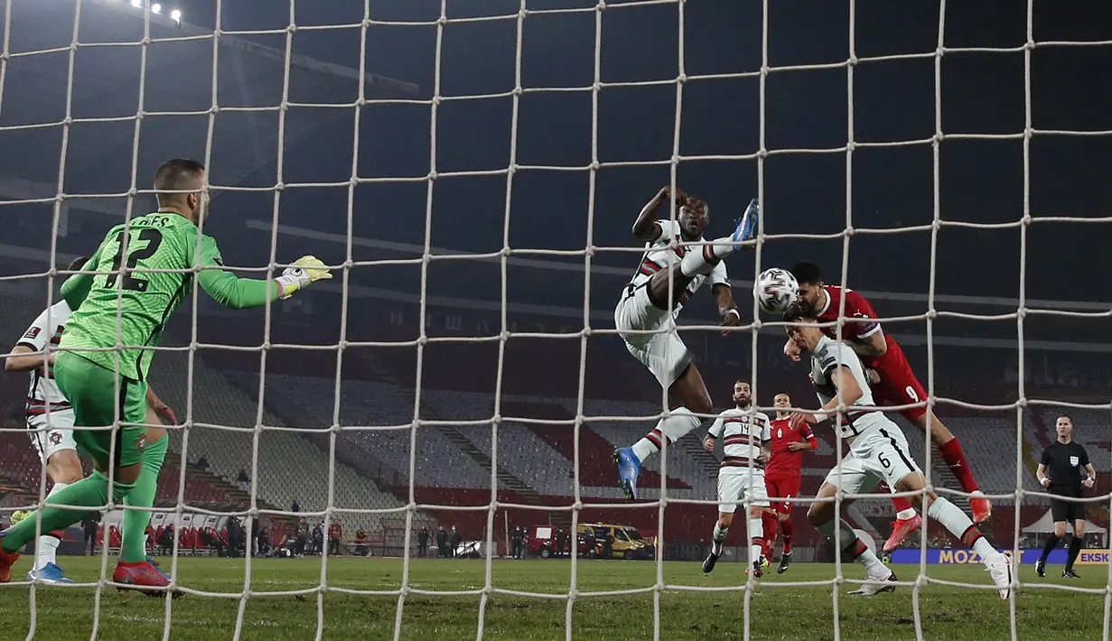 Striker Serbia, Aleksandar Mitrovic (kanan) melepaskan sundulan yeng berbuah gol pertama ke gawang Portugal dalam laga Kualifikasi Piala Dunia 2022 Zona Eropa Grup A di Rajko Mitic Stadum, Belgrade, Sabtu (27/3/2021). Serbia bermain imbang 2-2 dengan Portugal. (AFP/Pedja Milosavljevic)