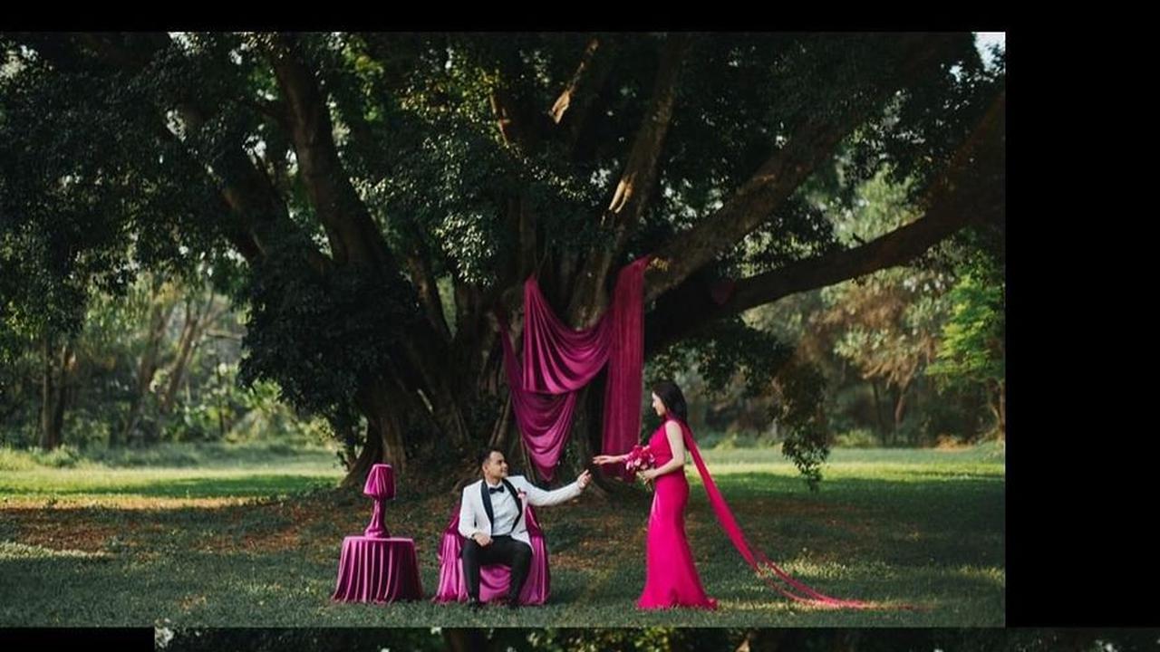 Febby dan Drajad berpose di depan pohon besar, menciptakan suasana romantis dengan nuansa teduh dan sejuk di sekelilingnya.<br><br>