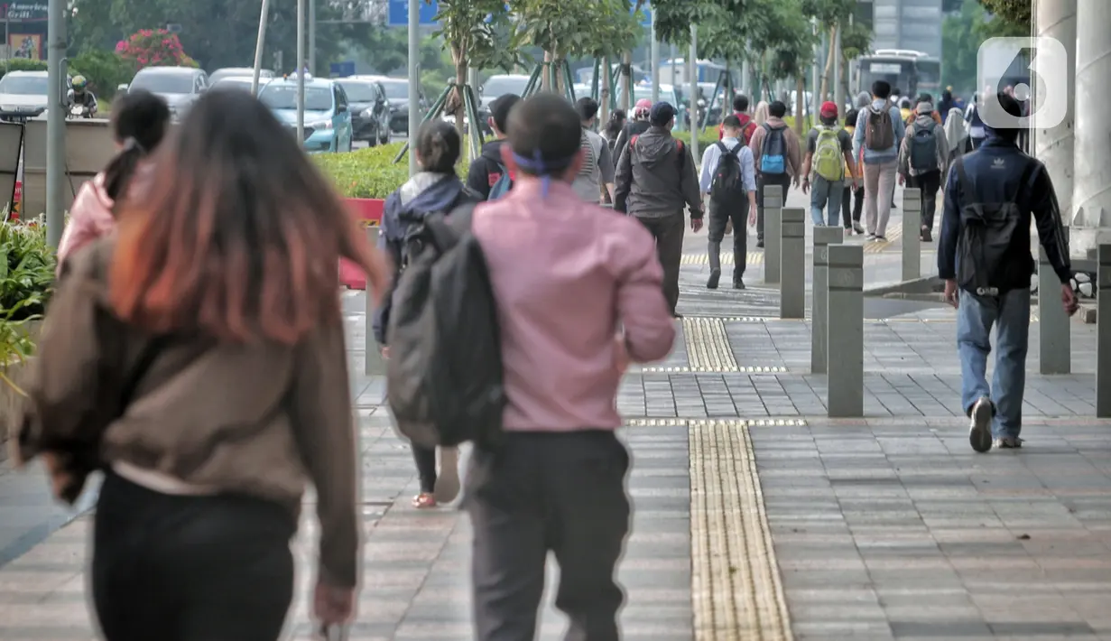 <p>Pegawai pulang kerja berjalan di trotoar Jalan Sudirman, Jakarta, Selasa (12/5/2020). Pemerintah memberi kelonggaran bergerak bagi warga berusia di bawah 45 tahun untuk mengurangi angka pemutusan hubungan kerja (PHK) akibat pandemi virus corona COVID-19. (Liputan6.com/Johan Tallo)</p>