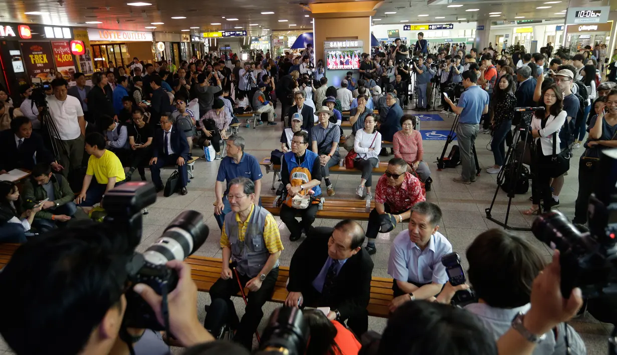 Orang-orang melihat layar TV yang menampilkan berita pertemuan Presiden AS Donald Trump dan pemimpin Korea Utara Kim Jong-un di Seoul Railway Station, Korsel, Selasa (12/6). Untuk pertama kalinya dalam sejarah, Trump dan Kim bertemu. (AP/Ahn Young-joon)