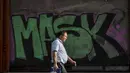 Seorang pria tanpa masker berjalan dekat grafiti di pusat kota Tel Aviv, Minggu (18/4/2021). Israel mencabut aturan wajib masker di ruang publik dan membuka kembali sekolah sepenuhnya dalam upaya menuju normalisasi setelah kampanye vaksinasi Covid-19 berjalan sukses. (AP Photo/Oded Balilty)