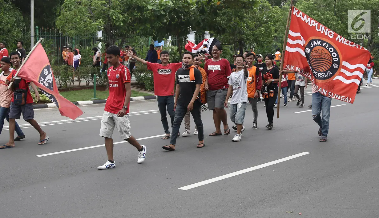 Jakmania berjalan kaki menuju Balai Kota saat akan merayakan kemenangan Persija di Liga I, Jakarta, Sabtu (15/12). Persija kembali meraih juara Liga Indonesia setelah 17 tahun. (Liputan6.com/Herman Zakharia)