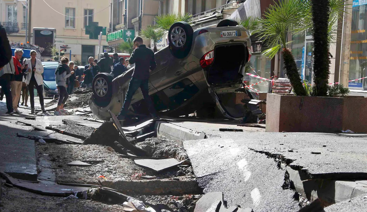 Warga melihat mobil yang terbalik dan jalanan yang hancur akibat banjir di Cannes, Prancis, Minggu (4/10/2015). Akibat peristiwa itu, sebanyak 16 warga dilaporkan tewas. (REUTERS/Eric Gaillard) 
