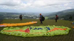 Paraglider bersiap untuk lepas landas dari lereng bukit di Puncak, Bogor, Jawa Barat, Kamis (2/12/2021). Destinasi wisata alam Bukit Paralayang Puncak Bogor sangat cocok untuk dikunjungi pada liburan akhir pekan bersama keluarga, sahabat maupun pasangan tercinta. (Goh Chai Hin/AFP)