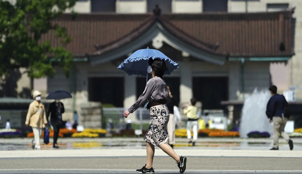 Seorang wanita mengenakan masker untuk mencegah penyebaran virus corona berjalan-jalan di taman di Tokyo (21/4/2021). Ibukota Jepang mengonfirmasi lebih dari 840 kasus virus corona baru pada hari Rabu. (AP Photo/Eugene Hoshiko)